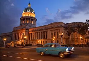 Traditional old American car speeding past the Capitolio building at night