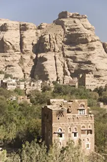 Yemen Prints: Traditional tall brick-built houses in village beneath sandstone cliff