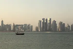 Dhow Prints: A traditional wooden dhow boat sails past modern skyscrapers in the West Bay financial district of Doha