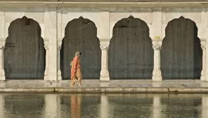 Traditionally dressed woman walking along one of the pools at the Bangla Sahib Sikh Temple in Delhi