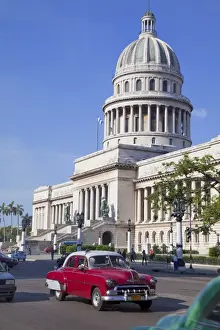Traditonal old American cars passing the Capitolio building, Havana, Cuba