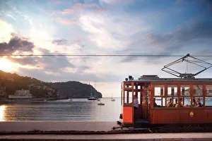 Medium Group Of People Prints: Tram at sunset set against yachts in bay, Soller, Mallorca, Balearic Islands