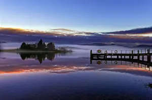 A tranquil view across the calm waters of Loch Shiel as dawn breaks on a misty winter morning