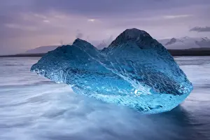 Translucent blue iceberg washed ashore on Breidamerkursandur black sands