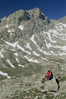 Walker Prints: Trekker resting on a rock in the high mountains of
