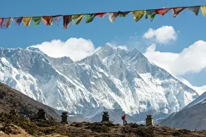Flag Prints: A trekker on their way to Everest Base Camp, Mount Everest is the peak to the left