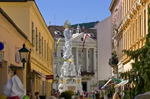 Hauptplatz Prints: The Trinity Column dating from 1714 and people walking around Hauptplatz surrounded by 18th century buildings