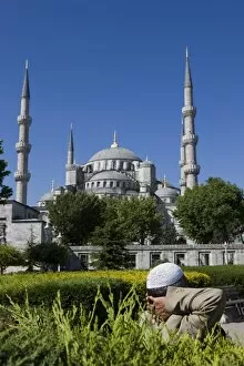 Images Dated 30th May 2008: Turkish man with traditional headware relaxing in Sultanahmet Square in front of the Blue Mosque
