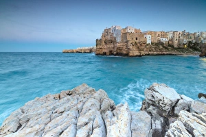 Turquoise sea at dusk framed by the old town perched on the rocks, Polignano a Mare