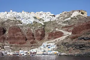 Typical Greek village perched on volcanic rock with white and blue houses and windmills