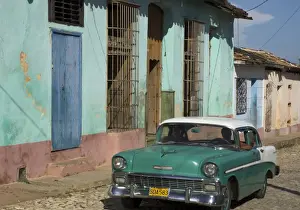 Cuban Prints: Typical paved street with colourful houses and old American car, Trinidad