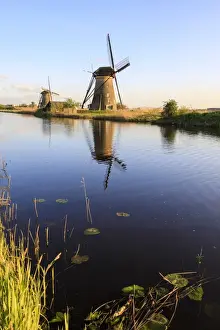 The Netherlands Prints: Typical windmills reflected in the canal framed by grass in spring, Kinderdijk, UNESCO