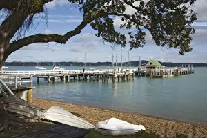 North Island Prints: Upturned boats on beach with pier to wharf in bay framed by Pohutukawa tree branches