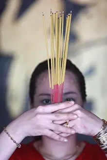 Hands Clasped Prints: Vietnamese woman in red traditional long dress Ao Dai praying with incense sticks