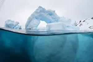 Above and below view of an arch formed in an iceberg at Cuverville Island, Ererra Channel