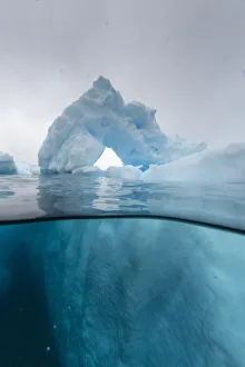 Above and below view of an arch formed in an iceberg at Cuverville Island, Ererra Channel