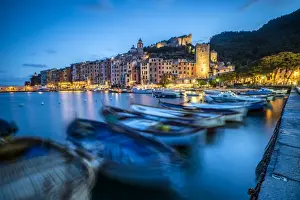 Cinque Terre Prints: View of blue sea and boats surrounding the colorful village at dusk, Portovenere