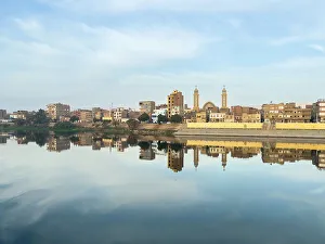 Dendera Prints: View of buildings reflected in the water on the Nile River