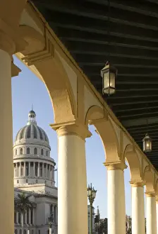 Capitolio Prints: A view of the Capitolio seen through the arches of a colonial style arcade in central Havana