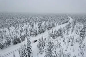 Rural Road Collection: View from above of a car travelling icy road in the middle of the frozen forest covered with snow