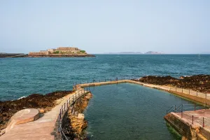 Guernsey Prints: View of Castle Cornet from seawater bathing pools in St Peter Port in Guernsey on a clear day with blue water