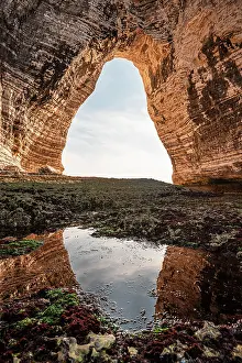 Cliffside Prints: View of chalk cliff arch with mirror reflection in tidal pool at low tide in Etretat France