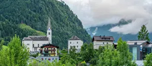 Salzburg Prints: View of church and buildings in Kaprun during summer with green mountains in the background in Salzburg Austria