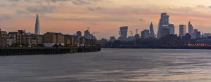 View of The City skyline at sunset from the Thames Path, London, England, United Kingdom