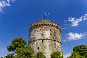 Greek Flag Prints: View of the citys landmark The White Tower, with Greek flag waving on top, Thessaloniki