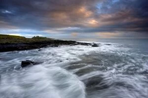 View along coastline on a stormy day towards the ruins of Dunstanburgh Castle