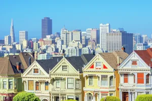 Neighborhood Prints: View of colorful Victorian houses with city skyline in the background in San Francisco California