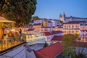 Terrace Prints: View of colourful buildings and red rooftops at dusk in the Alfama District