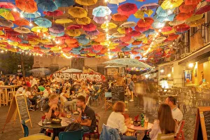 View of colurful umbrellas and restaurants on via Gisira at night, Catania, Sicily, Italy, Europe