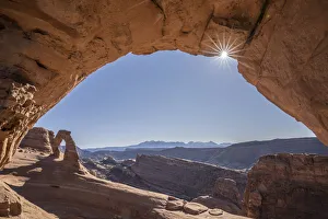 View of Delicate Arch through Frame Arch with sunburst, Arches National Park, Utah