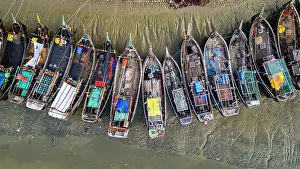 Stalls Prints: View of the fish market with boats moored along the shore during the early morning in Chittagong