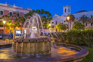 Water Fountain Prints: View of fountain and church bell tower in Placa des Born at dusk