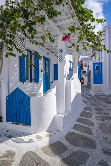 Shutters Prints: View of girl walking through whitewashed narrow street, Mykonos Town, Mykonos