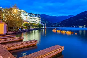 Waterscape Prints: View of Grand Hotel by Lake Zell at dusk with boats and mountains in background in Salzburg