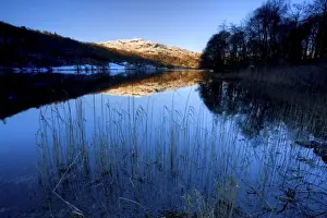 View across Grasmere on snowy winter morning with sunlight on distant fells