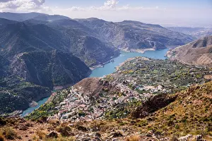 Destinations Prints: View of Guejar Sierra village alongside the blue Guenja Embalse lake at the foot of the Sierra Nevada in Spain