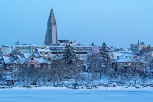 Magical Prints: View of the Hallgrimskirkja Church and city skyline of Reykjavik from Tjornin lake at sunset in winter