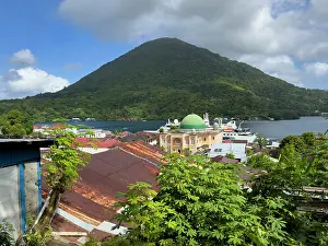 Maluku Prints: View of the harbor and buildings of Banda Neira with a mountain backdrop on the island in Indonesia