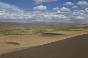 Barren Prints: View down a huge sand dune towards a ger dotted plain and distant hills on a summer evening