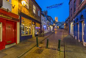 View of illuminated Lincoln Cathedral viewed from the cobbled Steep Hill at dusk