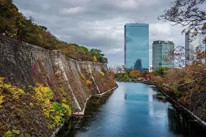 Heritage Site Prints: View along the inner Osaka Castle moat with autumnal trees and Crystal tower and CBD in the background