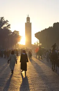 Koutoubia Prints: View towards the Koutoubia Minaret at sunset with local people walking through the scene