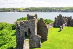 Sites Prints: View of Llansteffan Castle ruins with River Tywi and village in the background in Carmarthenshire