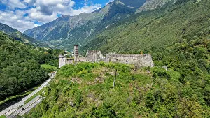Swiss Prints: View of Mesocco castle on a hill surrounded by mountains and greenery in Switzerland under a cloudy sky