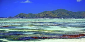 Aquatic Prints: View of Praslin Island from Anse Source dArgent on La Digue in Seychelles during clear weather