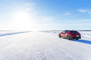 What's New: Side view of a red car travelling on empty icy road on the frozen sea, Lulea, Norrbotten County